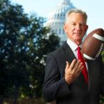 Tommy Tuberville holding a football in front of the U.S. Capitol building in Washington, D.C.